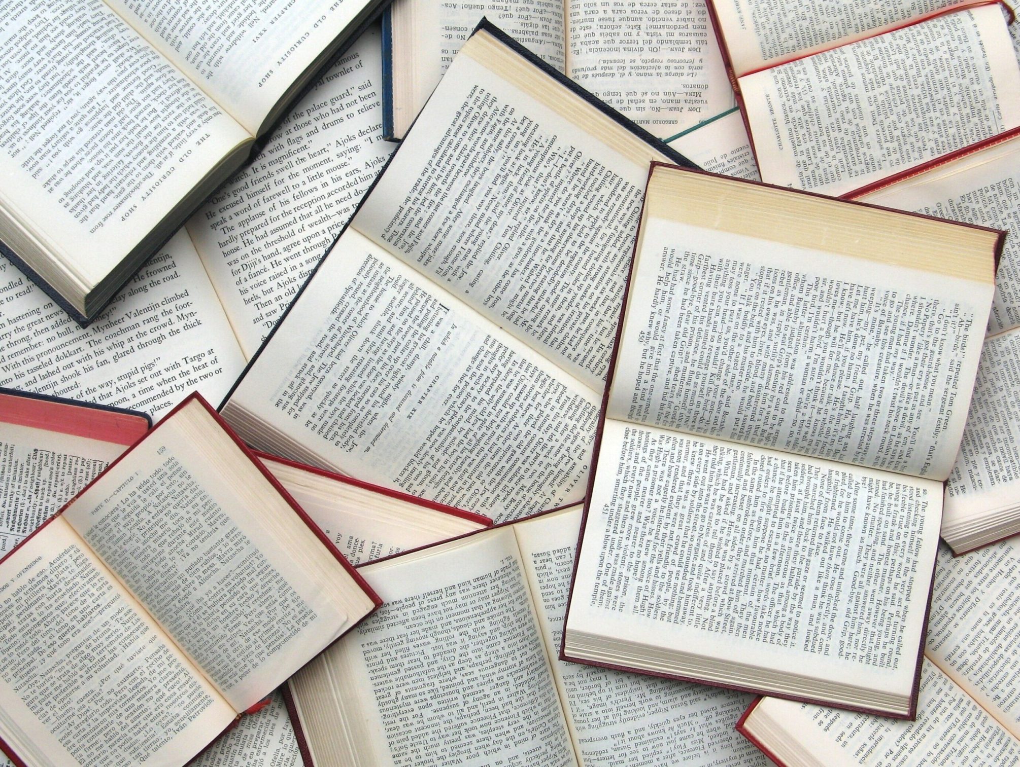 Aufgeschlgene Bücher, die übereinadner liegen und sich teils verdecken.